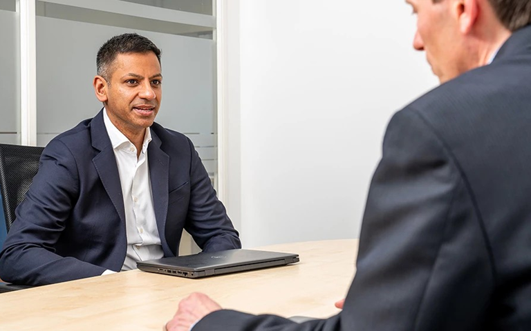 Two business people sitting across a table in a meeting